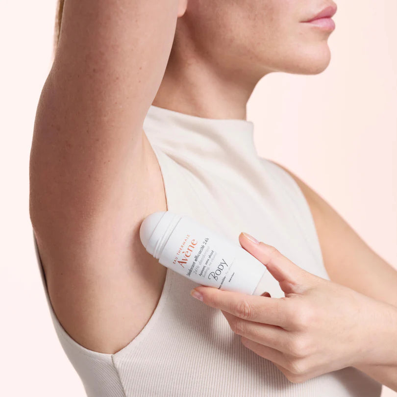 Person applying a white bottle of body lotion to their arm against a light background