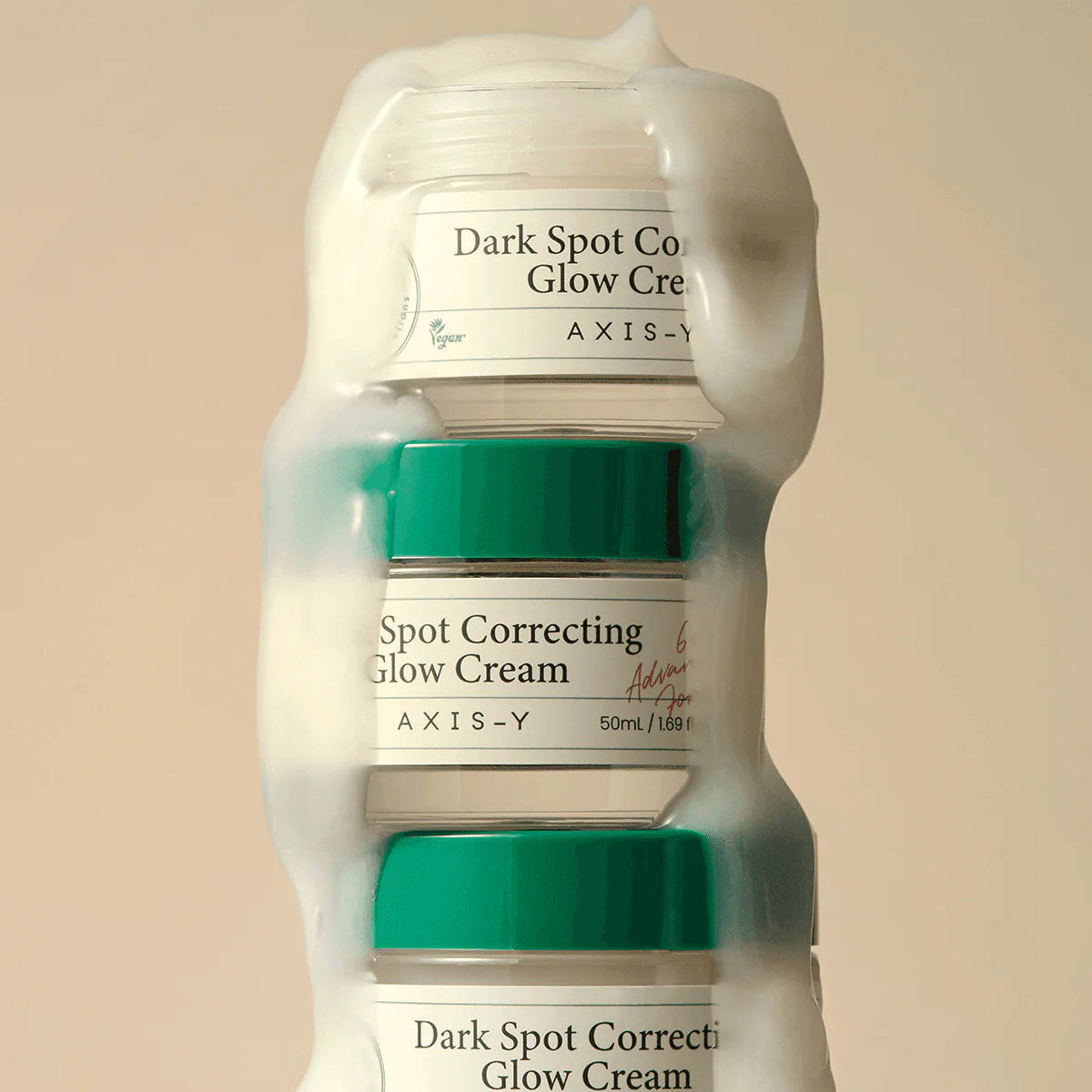 Three bottles of AXIS-Y Dark Spot Correcting Glow Cream on a beige background
