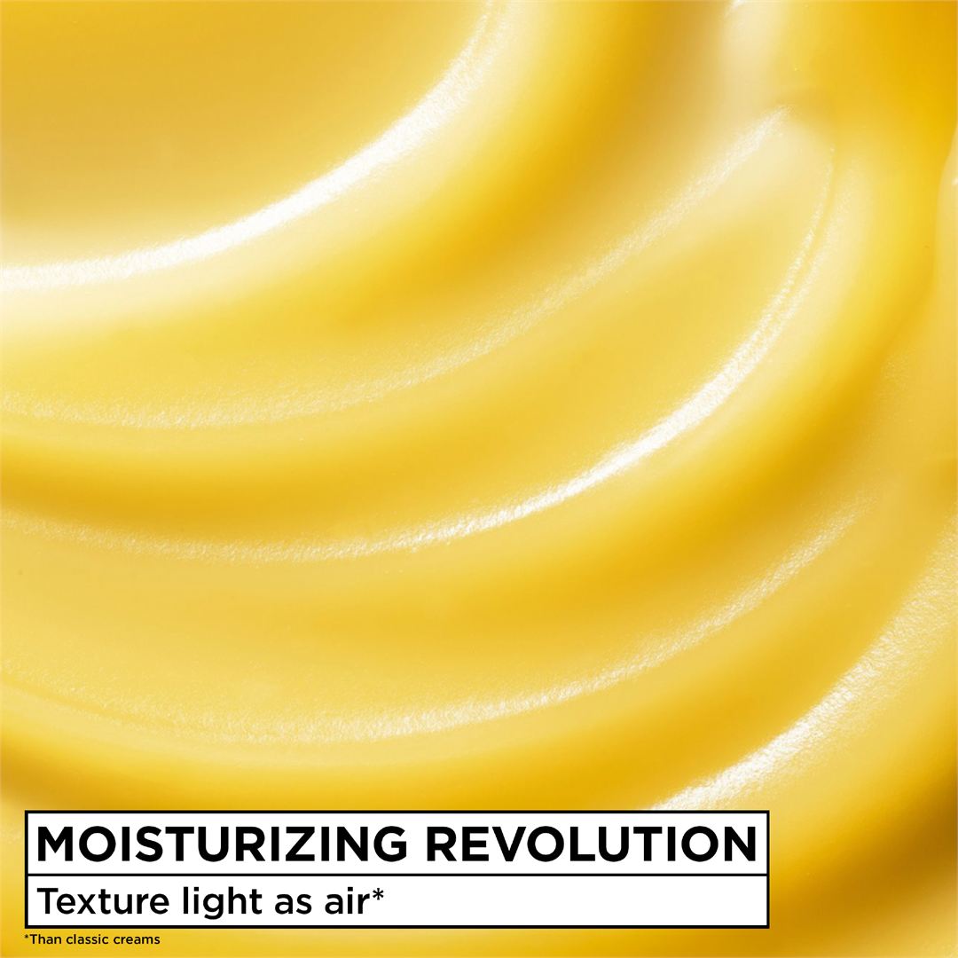A close-up of a smooth, creamy yellow product texture with soft swirls and a white label at the bottom reading 'MOISTURIZING REVOLUTION' and 'Texture light as air*'.