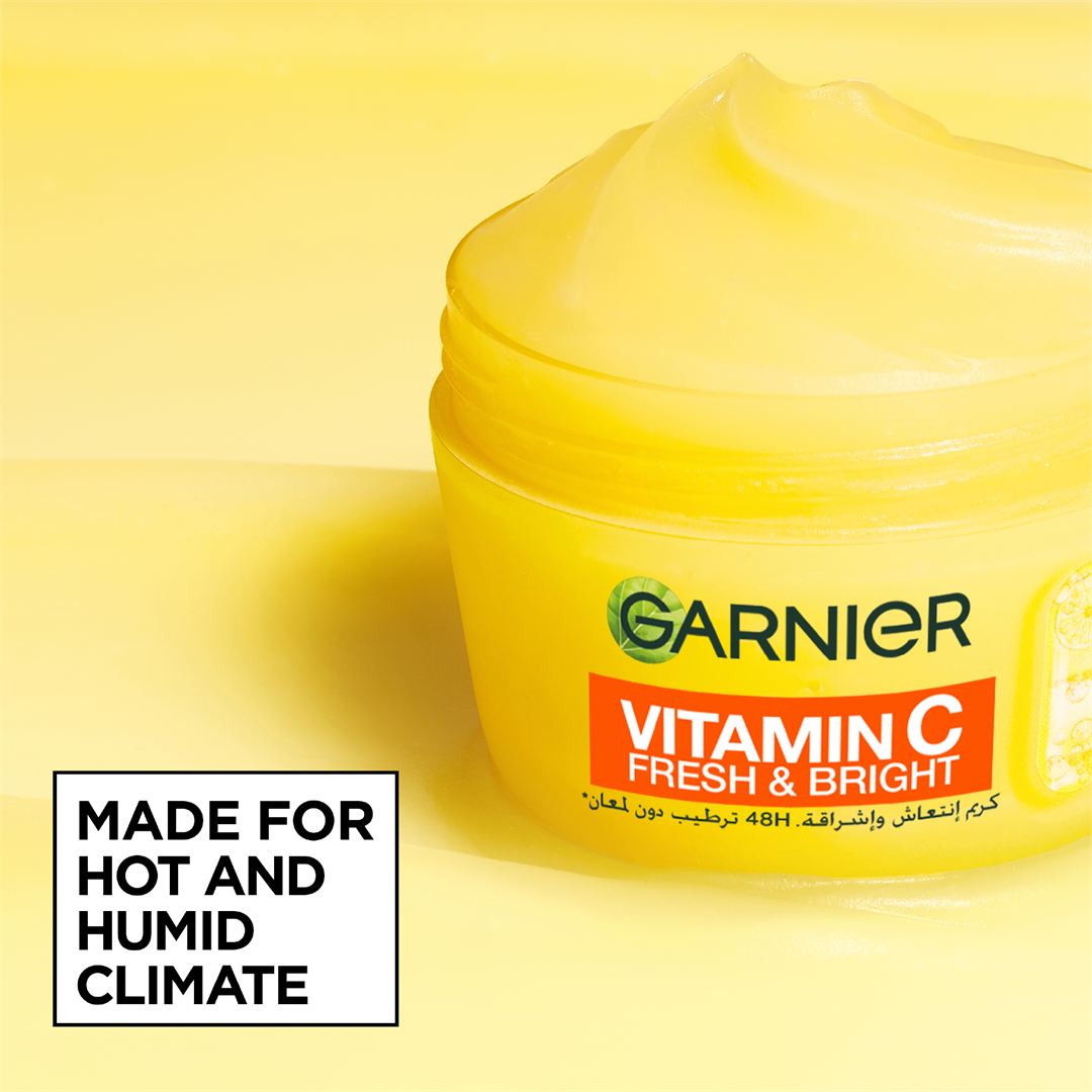 A jar of Garnier Vitamin C Fresh & Bright moisturizer shown on a bright yellow background, with a white text box that reads 'MADE FOR HOT AND HUMID CLIMATE'.