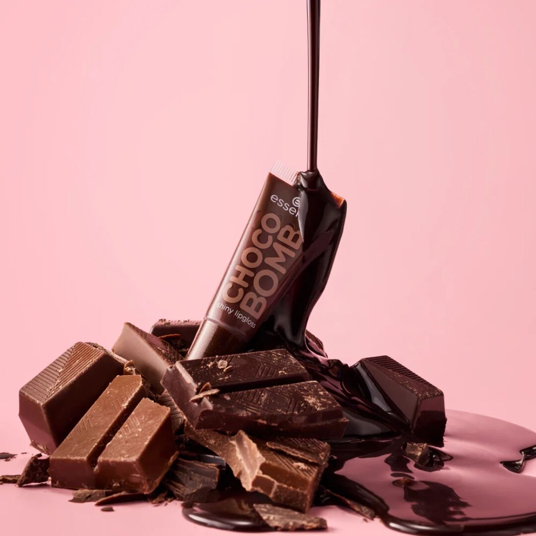 Chocolate bars with an Essence Choco Bomb Lip Gloss packaging on a pink background